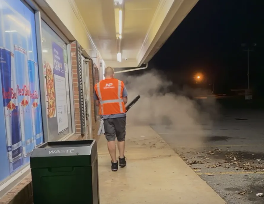 NightPort technician clearing accumulated debris from a commercial storefront edge at night
