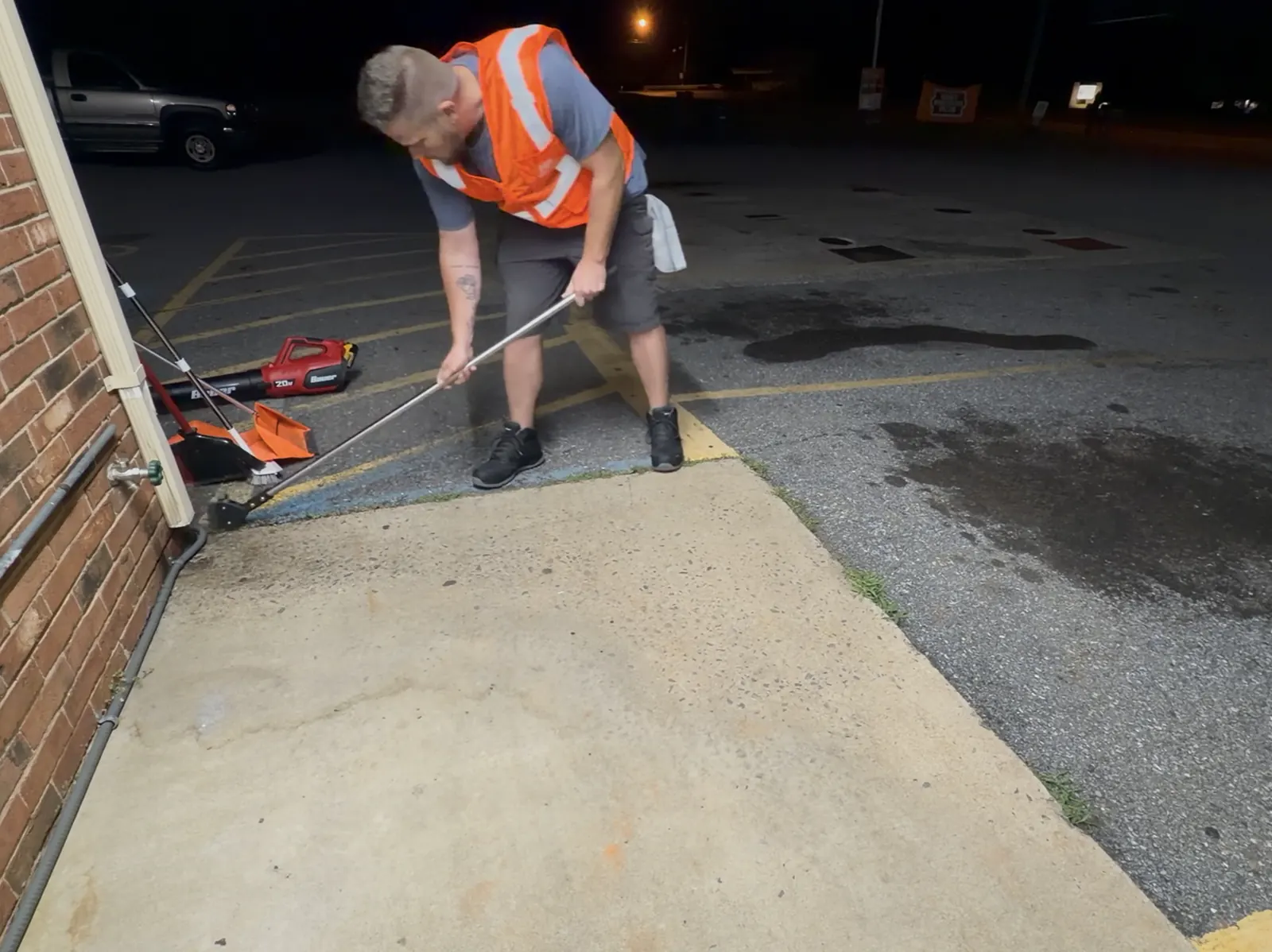 NightPort technician hand-detailing litter from a tight curb and building edge